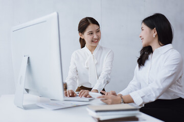 Fototapeta premium Young business women working on laptop with happy and smile face with co-worker behind her in office spec.