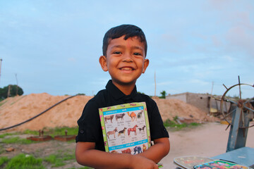 Cute little boy standing outdoor and funny smiley face and holding book,