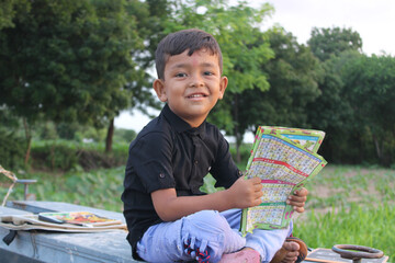 Cute little boy standing outdoor and funny smiley face and holding book,