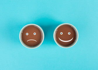 Cup of coffee with  a sad and a happy face, positive and negative mindset, support and evaluation concept, emotion