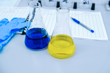 Glass flasks with a lilac yellow reagent are in the foreground in the laboratory.