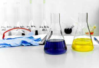 Two glass flasks with a lilac yellow reagent are in the foreground in the laboratory.