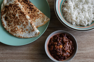 Chili con carne in a bowl accompanied by white rice and quesadillas