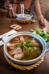 Turistas almorzando deliciosa sopa vietamita Pho Bo, con fideos, carne y verduras frescas