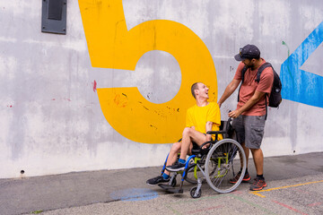 Disabled person in a wheelchair with a cement wall, having fun with a friend