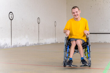 A disabled person in a wheelchair at a Basque pelota game fronton