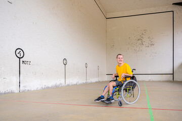A disabled person in a wheelchair at a Basque pelota game fronton smiling