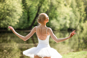 ballerina girl, in a white tutu, trains in the park, in the early morning. Graceful girl, secrets...