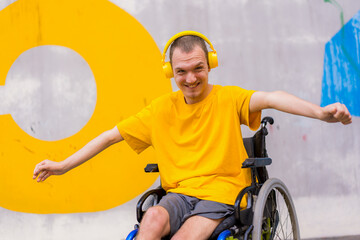 Fototapeta na wymiar Disabled person in a wheelchair listening to music with headphones, dancing and smiling