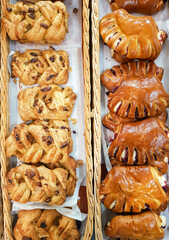 Delicious homemade sweet yeast buns with fresh berries, nuts and cinnamon in pastry shop. Products for a quick snack.