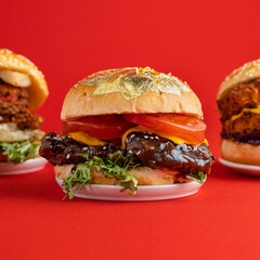 Beef Cheese Burger Sesame Edible Gold Foil Editorial Food Photography Red Backdrop with Space for Text 