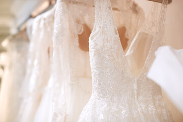 Close Up Of Beautiful Bridal Wedding Dresses Hanging On Rail In Shop