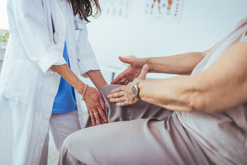 Photo of senior woman having some knee pain. She's at doctor's office having medical examination by...