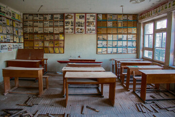 Aula escolar, con bancos vacíos y laminas en las paredes en una escuela soviética abandonada en...