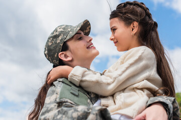 side view of woman in military uniform embracing daughter outdoors