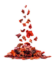 Dried red pepper falls on a pile close-up on a white background. Isolated