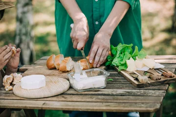 Foto op Canvas Stylish woman in green shirt make a snack with bread and cheese on a table in outdoor © Masson