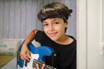 Portrait of young musician boy with his bass and a bandana on his forehead.