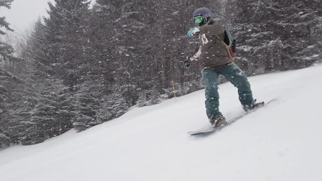 girl snowboarding on slopes during snowfall. female snowboarder in european ski center. side view.