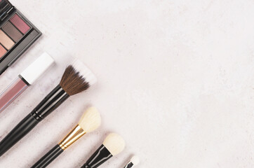 A collection of make-up tools scattered on the textured background.Various tools for visage, for personal and professional use. Flat lay, top view. Copy space.