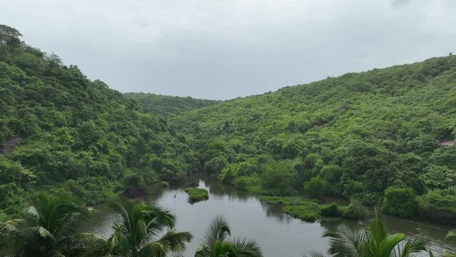 Aerial shot of Sweet lake surrounded by mountains covered with greenery in Goa, India
