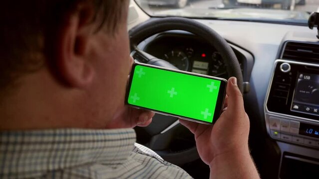 Man hold smartphone with green screen (Chroma key) with Car dashboard background.