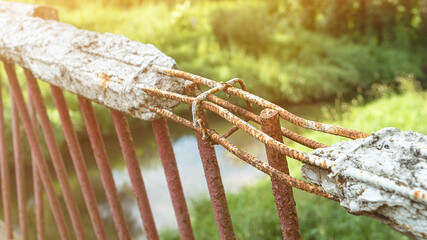 Fence with broken handrail made of reinforced concrete over river close view. Abandoned bridge in...