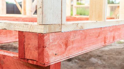 Red wooden beams and natural boards at construction site
