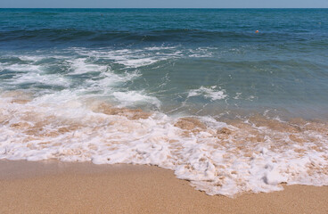 Fototapeta na wymiar Clear emerald green sea with white foam and clean sandy beach