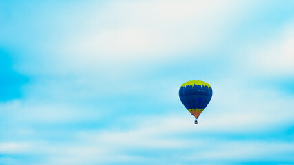 Hot air balloon in the blue cloudy sky