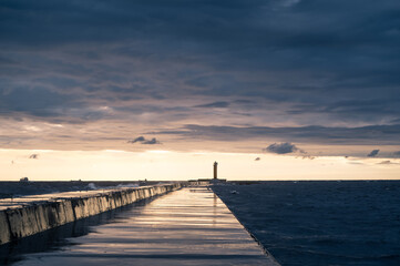 Fototapeta premium Scenic landscape of sunset over Baltic sea. Cloudy sky. Mangalsala mols. Way to lighthouse. Dramatic seascape.