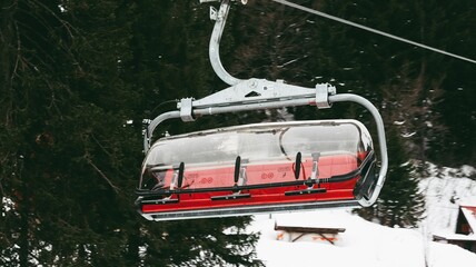 Winter ski resort, cable car with red seats and a hood on them, Jahorina, Bosnia and Herzegovina. © Milan Dokic/Wirestock Creators