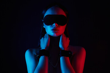 Fototapeta na wymiar Girl in handcuffs and mask. Beautiful young Woman in color lights