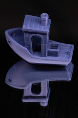 Vertical shot of a 3D printed boat on a mirrored surface