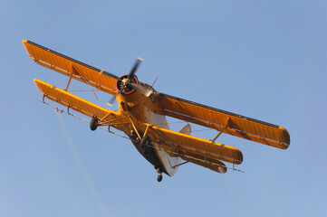 Agricultural airplane spraying pesticides on agricultural fields in summer