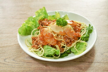 spaghetti topping slice sausage dressing fried chop pork and slice tomato in ketchup sauce with vegetableon plate   