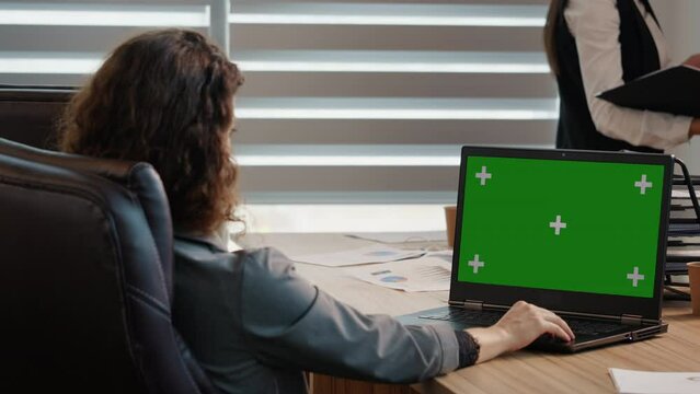 Side view business woman or female freelancer watching a webinar on green screen chroma key laptop. Girl looking at green screen laptop computer watching movie, video content.
