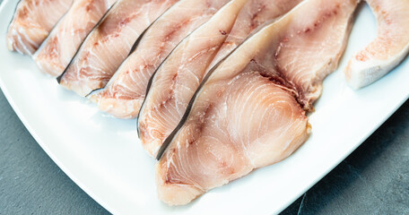 Close-up of various slices of raw swordfish, in a white plate, on a slate table..Tasty food from Italian cuisine and from the Mediterranean sea. Concept for a tasty and healthy meal.