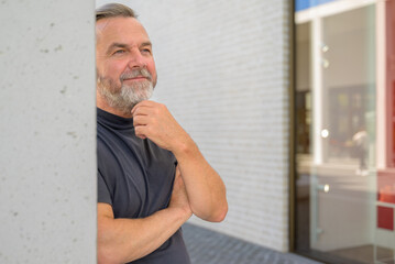 Thoughtful man leaning against a wall with a quiet smile