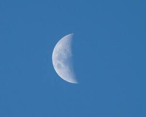 White half moon in a clear blue sky