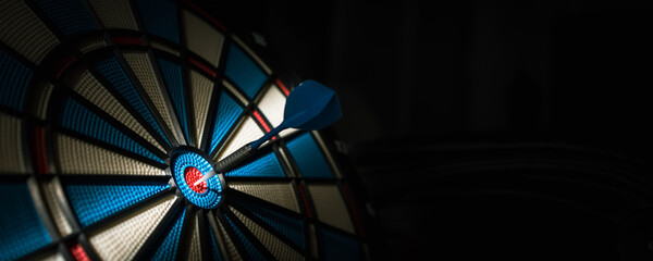 A dart hitting the center of target with copy space in dramatic light and shadow. Bullseye target...