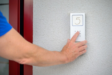 Man pressing a speaker phone for access to an apartment