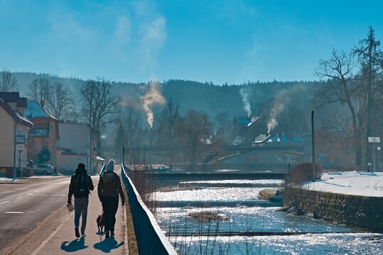 Couple walking with a dog near the river with a mountain in Ladek Zdroj, Poland