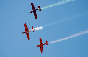 Silhouettes of training aircraft performing aerobatics on a clear sunny day.