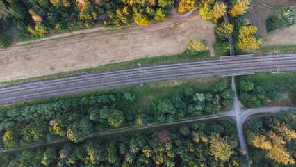 Train railroad tracks next to a forest and field. Top aerial view of German train system near Munich