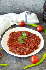 Adjika or chili paste. Hot chili peppers harissa sauce. Spicy paste appetizer on a dark background. close up