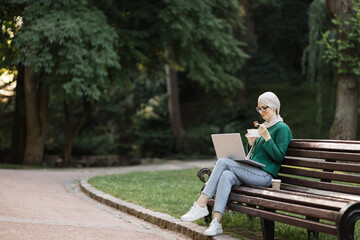 Fototapeta premium Attractive muslim business woman eating healthy salad while having break during work. Kind islamic female eating her salad while sitting on bench on the city park near her office building.