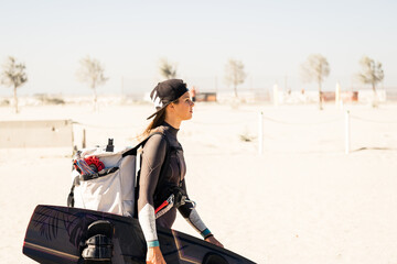 Beautiful girl focused and ready, comes to the beach with kitesurfing equipment - Sporty woman...