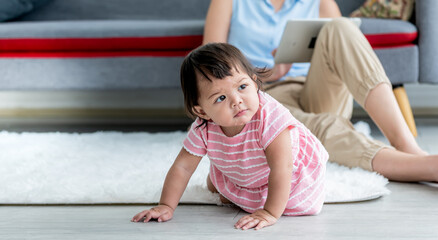 Naklejka premium Caucasian baby girl is 7 months old, sitting on the floor, learning to crawl with blur background of mothers, which is the development of a baby infant, to child concept.