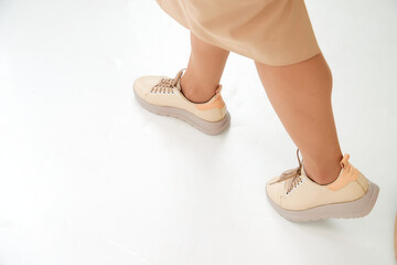 Beautiful sneakers on woman legs in the studio on white background. Fashionable shooting of a young girl with beautiful legs